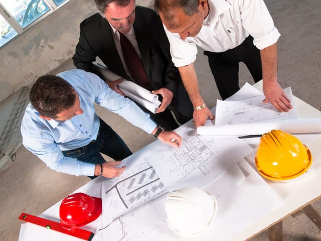 Three construction executives looking at drawings 1200x900