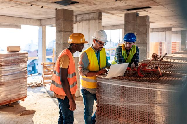 Three construction workers on site looking at an iPad 1200x800