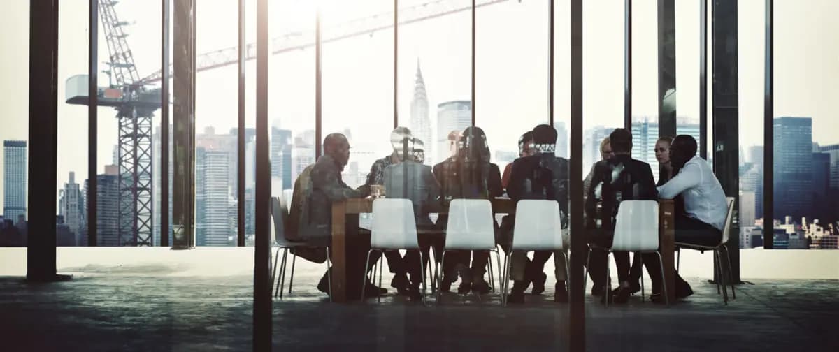 Employees sitting at a table having a meeting in the distance 1200x504