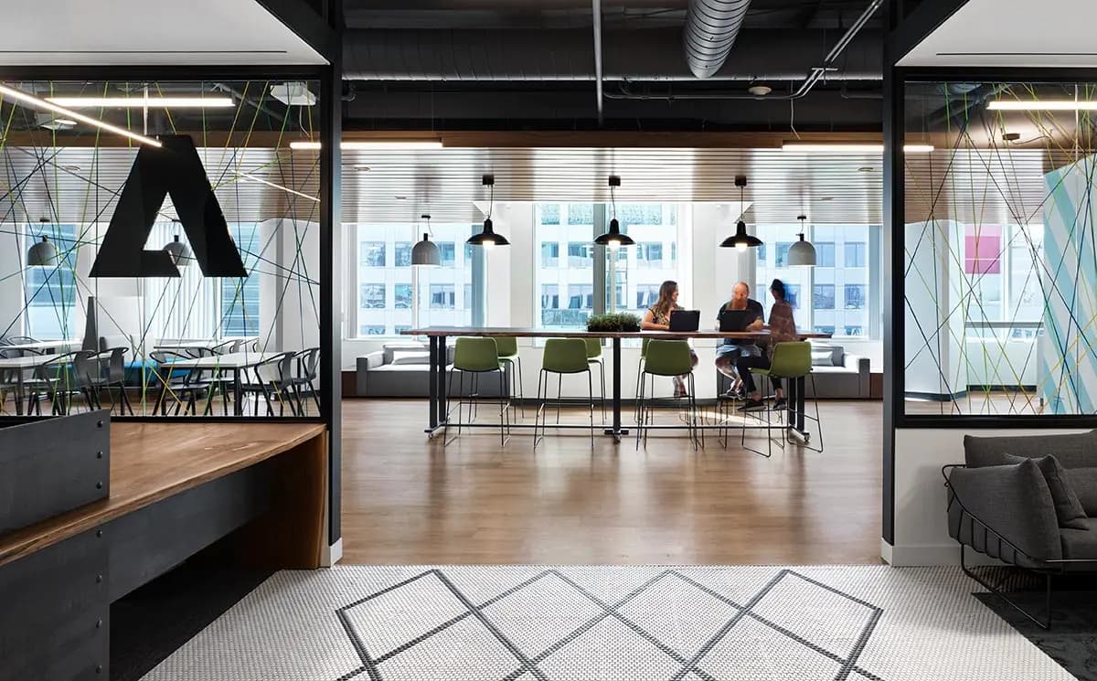 MARANT Adobe Systems Inc Canada - three employees talking at a desk in the distance