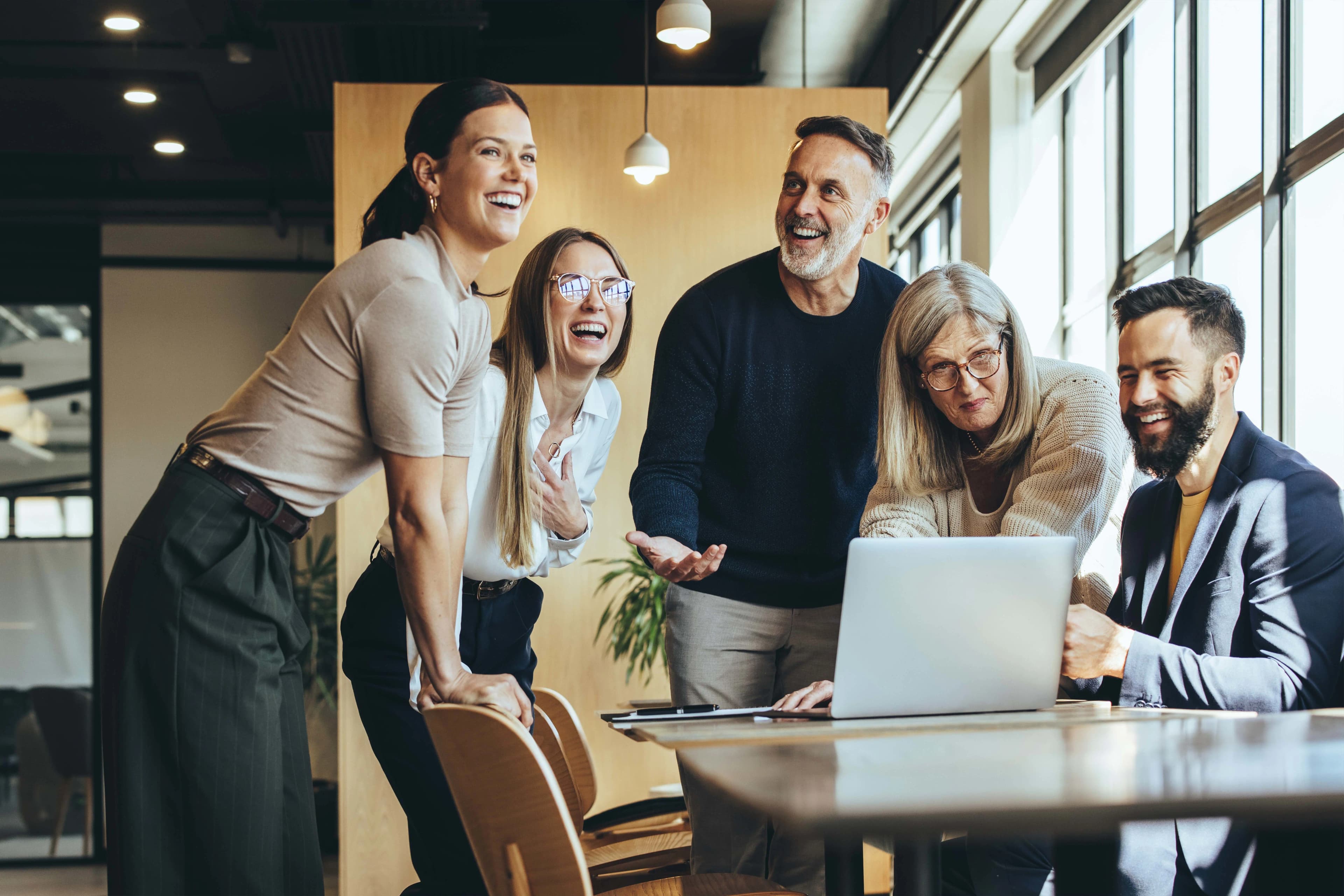 5 people talking around a laptop