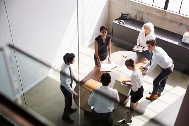 Six executives overhead shot standing around a table