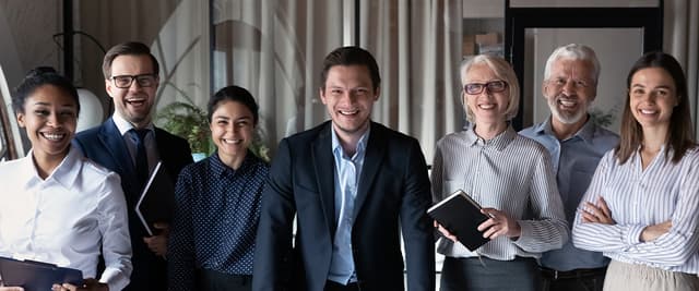 Seven employees standing and smiling 