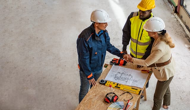 Over head shot three construction workers standing over drawings