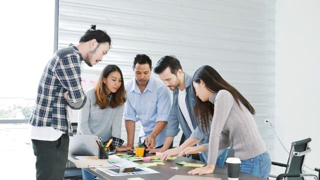 Five employee standing at a desk looking at construction documents