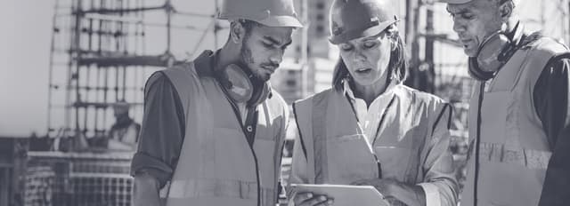 Three construction workers on site looking at an iPad