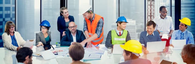 Construction workers at a table talking and looking at drawings 1200x400