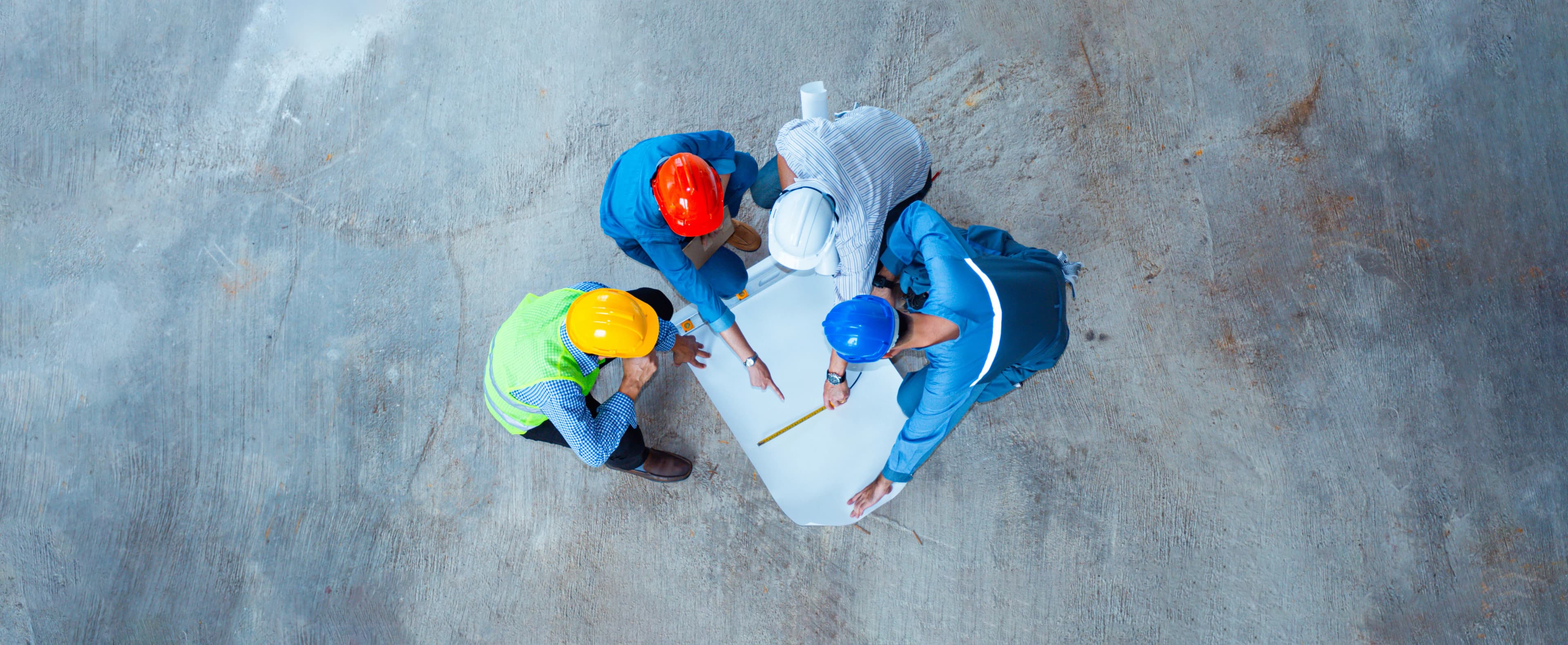 Over head shot of four construction workers standing looking at a drawing